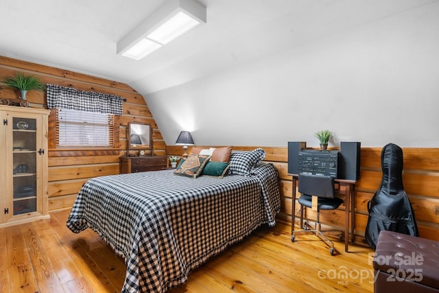 bedroom featuring hardwood / wood-style flooring, vaulted ceiling, and wood walls