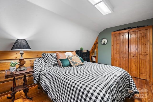 bedroom featuring hardwood / wood-style flooring, lofted ceiling, and a closet