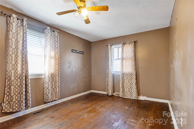 spare room featuring dark wood-type flooring, a textured ceiling, and ceiling fan