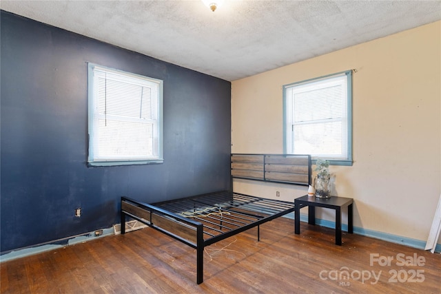 unfurnished bedroom featuring hardwood / wood-style floors, multiple windows, and a textured ceiling