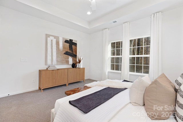 bedroom with a tray ceiling, radiator heating unit, ceiling fan, and carpet flooring