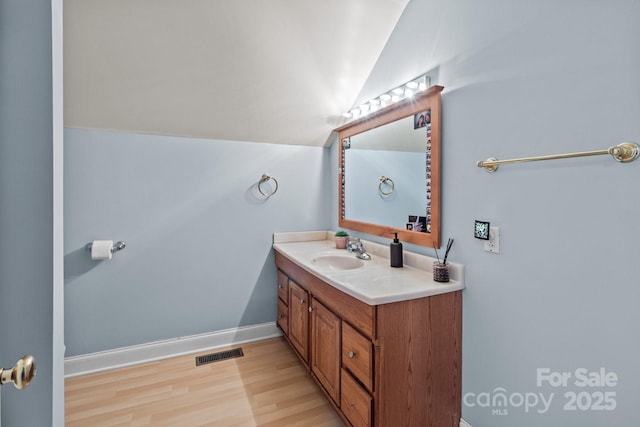 bathroom with vanity, lofted ceiling, and wood-type flooring