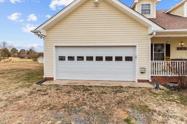 garage with a porch and a yard