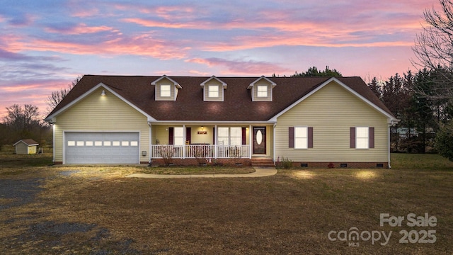 cape cod-style house with a porch, a garage, and a yard