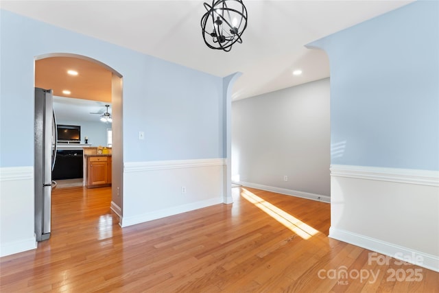 interior space with ceiling fan with notable chandelier and light hardwood / wood-style floors