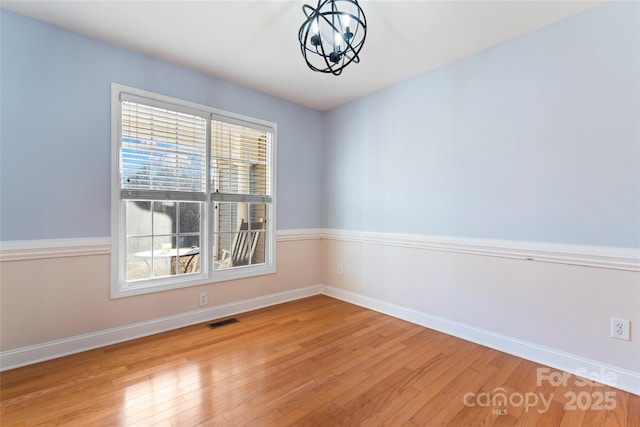 empty room featuring an inviting chandelier and light hardwood / wood-style flooring