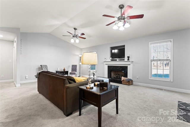 carpeted living room with a fireplace, vaulted ceiling, and ceiling fan