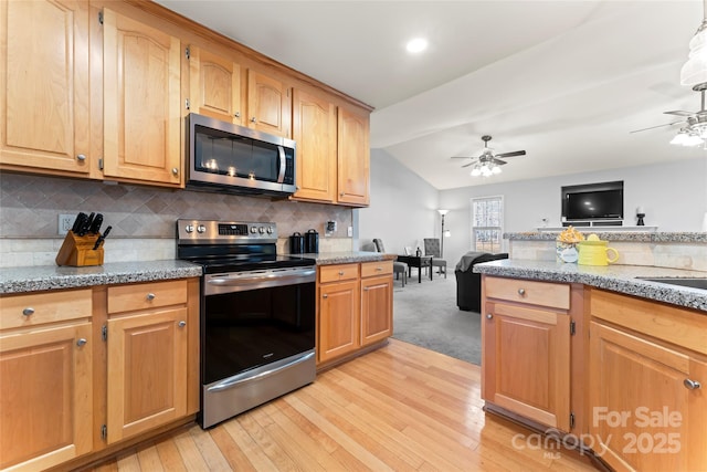 kitchen featuring ceiling fan, stainless steel appliances, vaulted ceiling, and light wood-type flooring