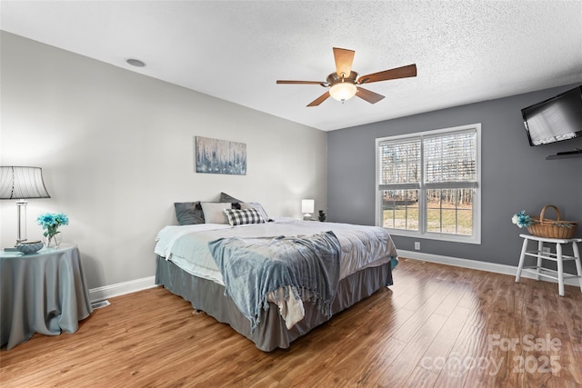 bedroom featuring ceiling fan, hardwood / wood-style flooring, and a textured ceiling