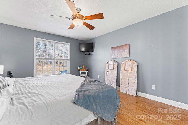 bedroom with hardwood / wood-style flooring, ceiling fan, and a textured ceiling