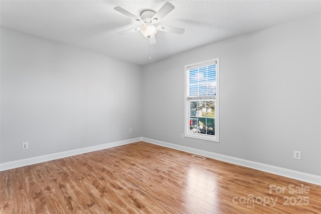 empty room with ceiling fan, hardwood / wood-style floors, and a textured ceiling