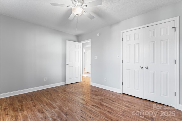 unfurnished bedroom with ceiling fan, wood-type flooring, a closet, and a textured ceiling