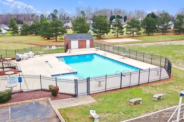 view of swimming pool featuring a yard, an outdoor structure, and a patio area