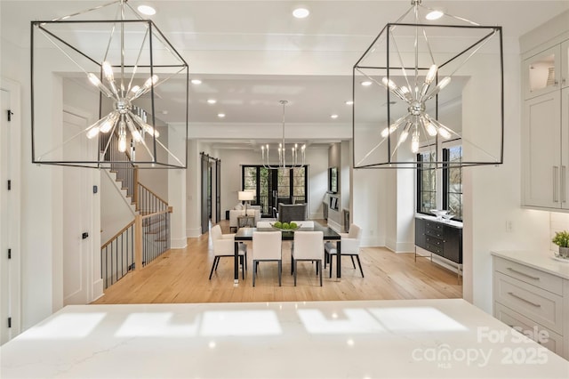 dining area with light wood-type flooring, an inviting chandelier, baseboards, and recessed lighting