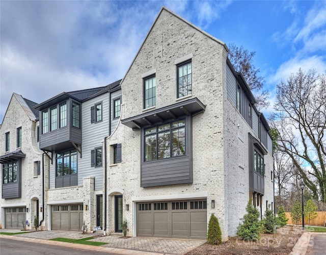 townhome / multi-family property featuring brick siding, decorative driveway, and an attached garage