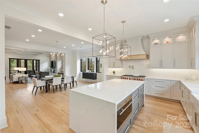 kitchen featuring light wood-style flooring, a kitchen island, visible vents, and open floor plan