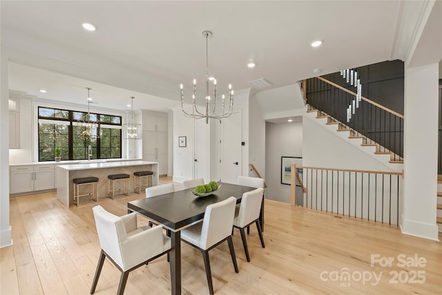 dining room featuring a notable chandelier, light wood finished floors, recessed lighting, visible vents, and ornamental molding