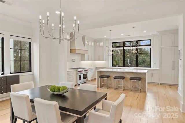 dining space with a chandelier, a wealth of natural light, visible vents, and light wood-style floors