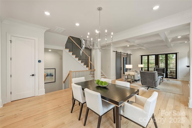 dining area featuring light wood finished floors, a barn door, stairs, and recessed lighting