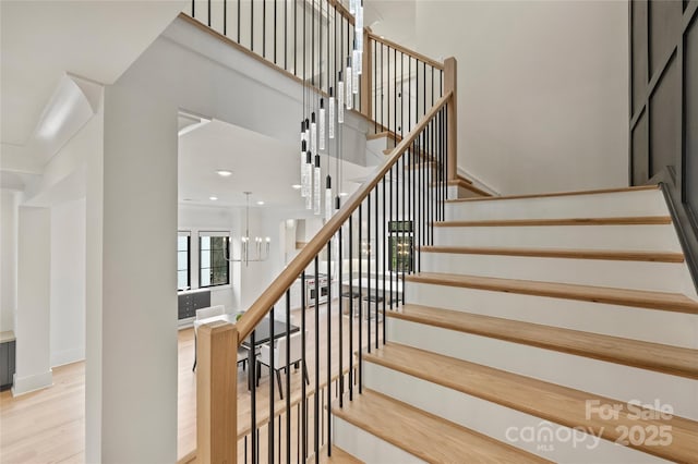 staircase featuring a chandelier and wood finished floors