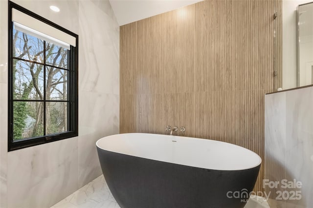 full bathroom featuring a soaking tub and tile walls