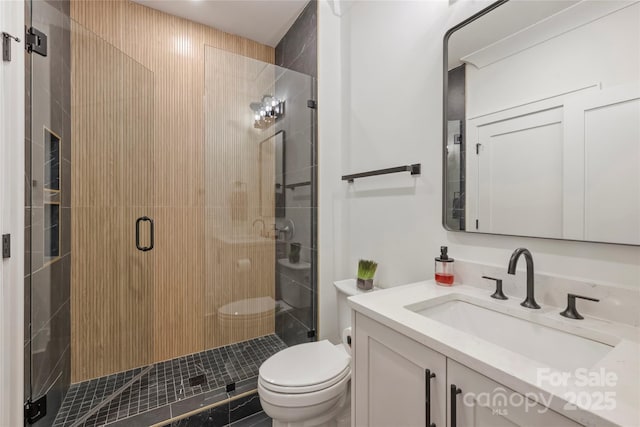 full bath featuring a stall shower, vanity, and toilet