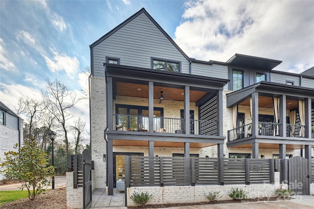 view of front of property with fence private yard, brick siding, and a balcony