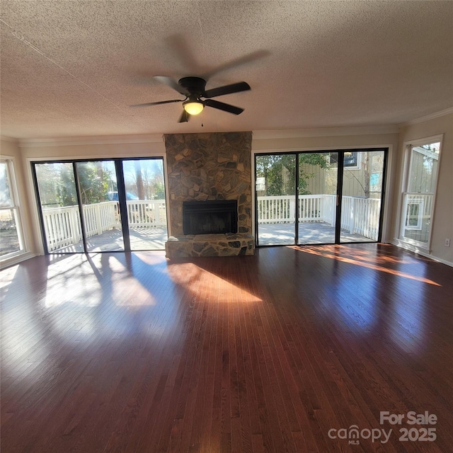 unfurnished living room featuring crown molding, hardwood / wood-style flooring, a stone fireplace, and plenty of natural light