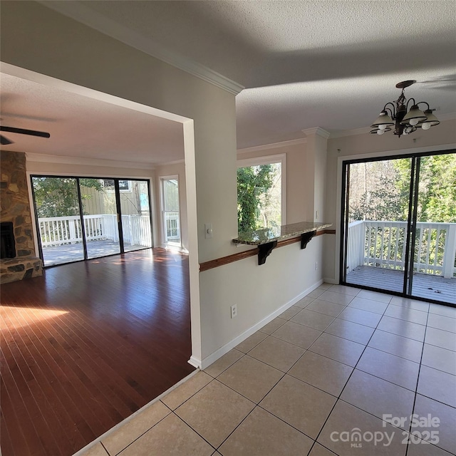 tiled spare room with ornamental molding, a healthy amount of sunlight, a fireplace, and a textured ceiling