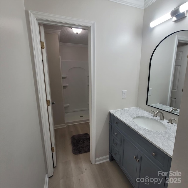 bathroom featuring wood-type flooring, vanity, walk in shower, crown molding, and a textured ceiling