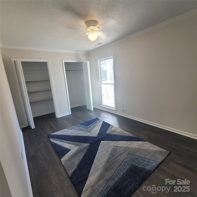 bedroom with crown molding, two closets, dark hardwood / wood-style floors, and a textured ceiling