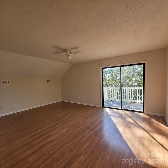 additional living space with ceiling fan, lofted ceiling, dark hardwood / wood-style floors, and a textured ceiling