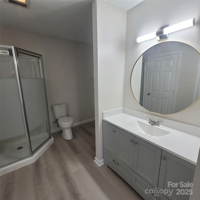 bathroom featuring toilet, a textured ceiling, vanity, a shower with door, and hardwood / wood-style flooring