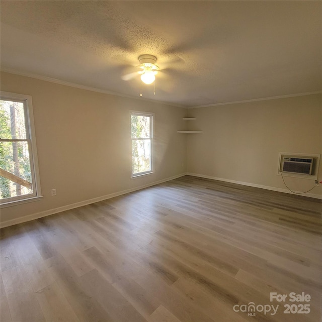 unfurnished room featuring crown molding, light hardwood / wood-style floors, a wall mounted AC, and a textured ceiling