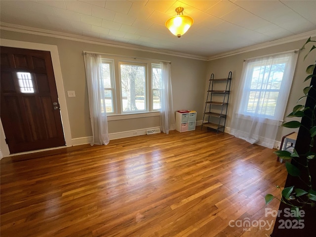 foyer entrance with ornamental molding, baseboards, and wood finished floors