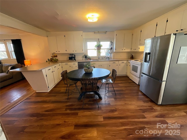 kitchen with white cabinets, appliances with stainless steel finishes, light countertops, and dark wood finished floors