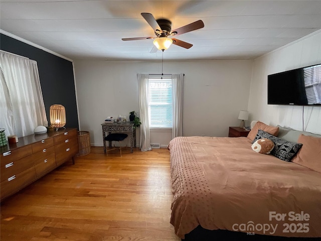 bedroom featuring light wood-type flooring, a ceiling fan, and crown molding