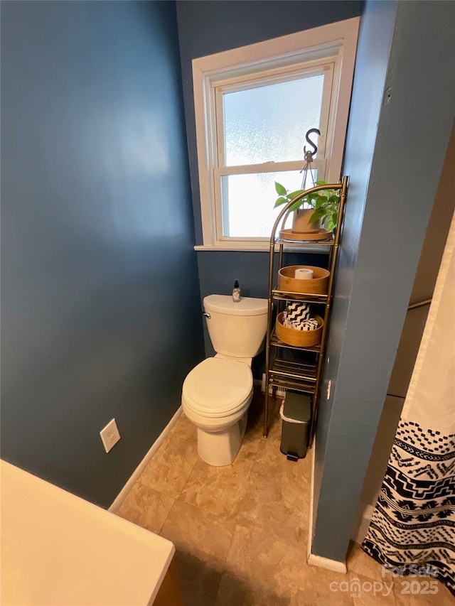 bathroom with toilet and baseboards