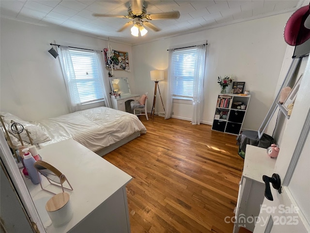 bedroom featuring ceiling fan, baseboards, and wood finished floors