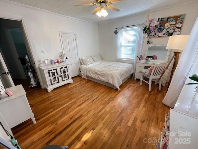 bedroom featuring a ceiling fan, crown molding, and wood finished floors