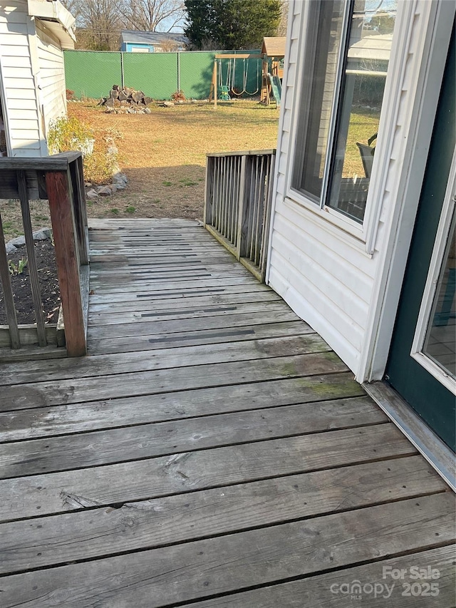 wooden terrace featuring a playground and fence