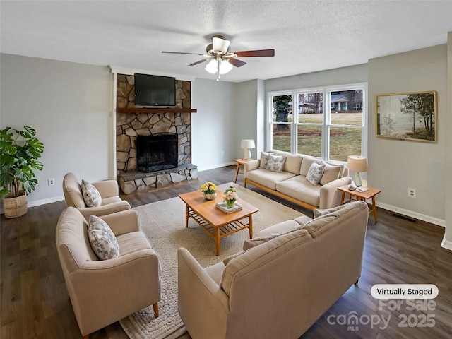 living room featuring ceiling fan, dark wood-type flooring, a textured ceiling, and a fireplace