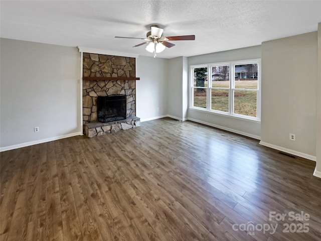 unfurnished living room featuring ceiling fan, a stone fireplace, dark hardwood / wood-style floors, and a textured ceiling