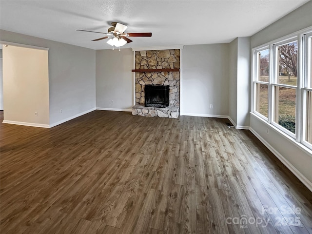 unfurnished living room with ceiling fan, a fireplace, dark hardwood / wood-style flooring, and a textured ceiling