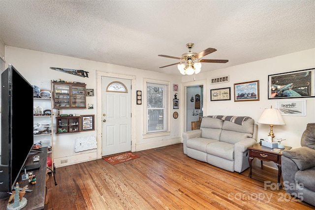 living room with ceiling fan, hardwood / wood-style floors, and a textured ceiling