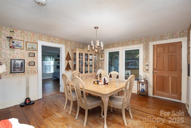 dining space with an inviting chandelier, wood-type flooring, and a textured ceiling