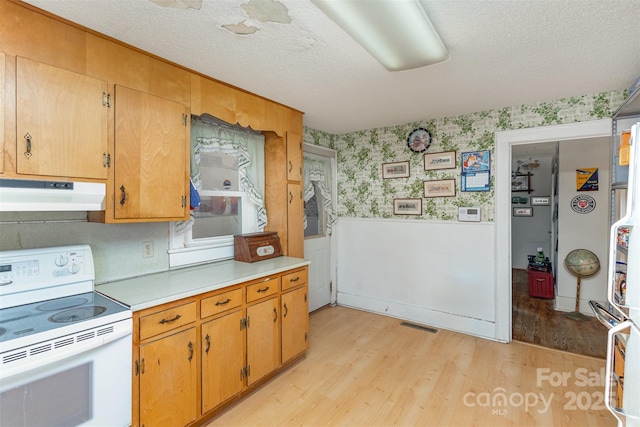 kitchen with light wood-type flooring, a textured ceiling, and white range with electric stovetop