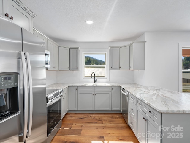 kitchen with sink, gray cabinets, stainless steel appliances, and light wood-type flooring