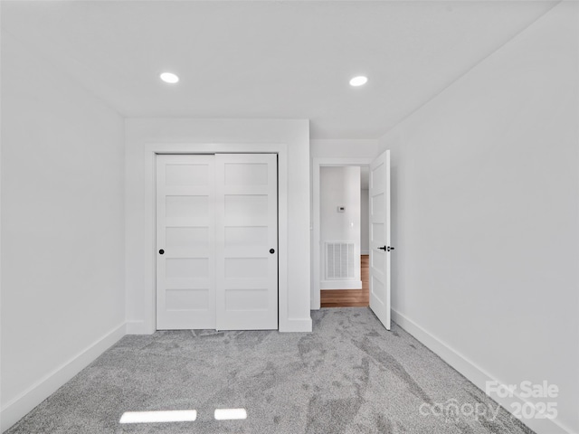 unfurnished bedroom with a closet and light carpet