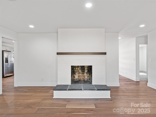 unfurnished living room with hardwood / wood-style flooring and a brick fireplace